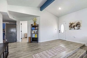 A spacious room with a wooden floor, a bookshelf, a door, and a wall-mounted artwork. - Unit A of Crystal Beach's Premier Triplex 2Bd 1Bth (Bolivar Peninsula)