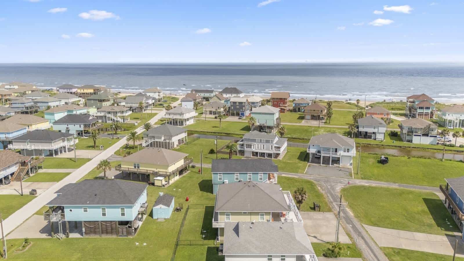 Una zona residencial costera con casas, una playa y una vista despejada del océano.