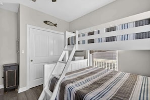 A bunk bed room with a ladder, a white door, and a fish decoration on the wall. - Bring the Whole Crew Sleeps 13 MerSea (Bolivar Peninsula)