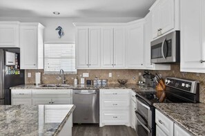 A kitchen with white cabinets, a stainless steel dishwasher, a double oven, and a microwave. - Bring the Whole Crew Sleeps 13 MerSea (Bolivar Peninsula)
