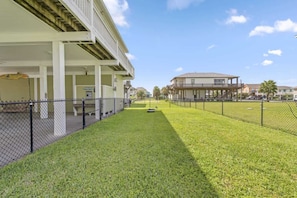A fenced outdoor area with a building in the background. - Bring the Whole Crew Sleeps 13 MerSea (Bolivar Peninsula)