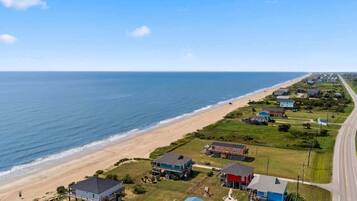 Vista aérea de una zona residencial costera con casas, una playa y una carretera.