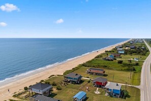 An aerial view of a coastal residential area with houses, a beach, and a road. - Beachfront Fire Pit  Gourmet Kitchen Views (Bolivar Peninsula)