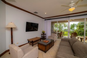 A living room with a sofa, armchairs, a coffee table, a TV, and a ceiling fan. - Bay Residence 8C 3 bdr 2 bath (Herradura)