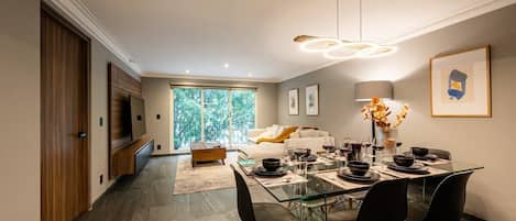Un espace repas moderne avec une table en verre, des chaises noires et un lustre.