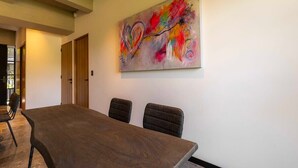 Una sala de conferències amb una taula llarga i quatre cadires, un quadre abstracte i colorit a la paret, i una porta al fons.