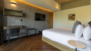 Habitació d'hotel moderna amb un llit gran, un escriptori amb una cadira, una televisió i una taula petita.