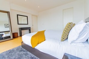 Ein Schlafzimmer mit Bett, Spiegel, Kamin und Tür.