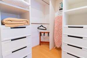 Ein begehbarer Kleiderschrank mit weißen Schubladen und einer Kleiderstange.