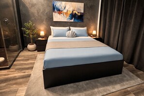 Ein modernes Schlafzimmer mit einem großen Bett, einem Bild an der Wand und einer Zimmerpflanze.