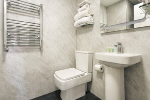 Ein modernes Badezimmer mit Toilette, Waschbecken, Handtuchhalter und Spiegel.