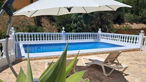 A swimming pool with a white fence, a white umbrella, and a stone patio with a lounge chair. - Villa in Cumbre del Sol—bookable for stays of 11 days or more (El Poble Nou de Benitatxell/Benitachell)