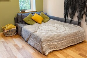 A cozy room with a bed, a basket, and a window. - Artsy Apt in Lawrenceville with deck & parking (Pittsburgh)