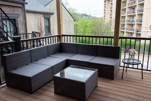 A covered outdoor seating area with a sectional sofa and a glass coffee table. - Artsy Apt in Lawrenceville with deck & parking (Pittsburgh)