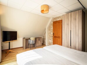 A bedroom with a bed, a desk with a chair, a television, and a wooden wardrobe. - Pet-free Texel Villa With Sauna (De Koog)