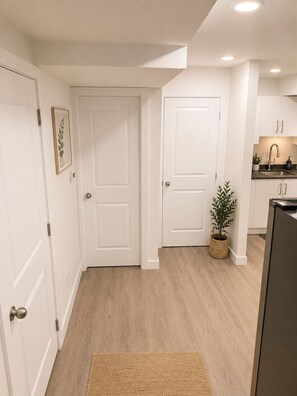 A modern kitchen with white cabinetry, a built-in oven, and a small potted plant. - Home away from home (Edmonton)