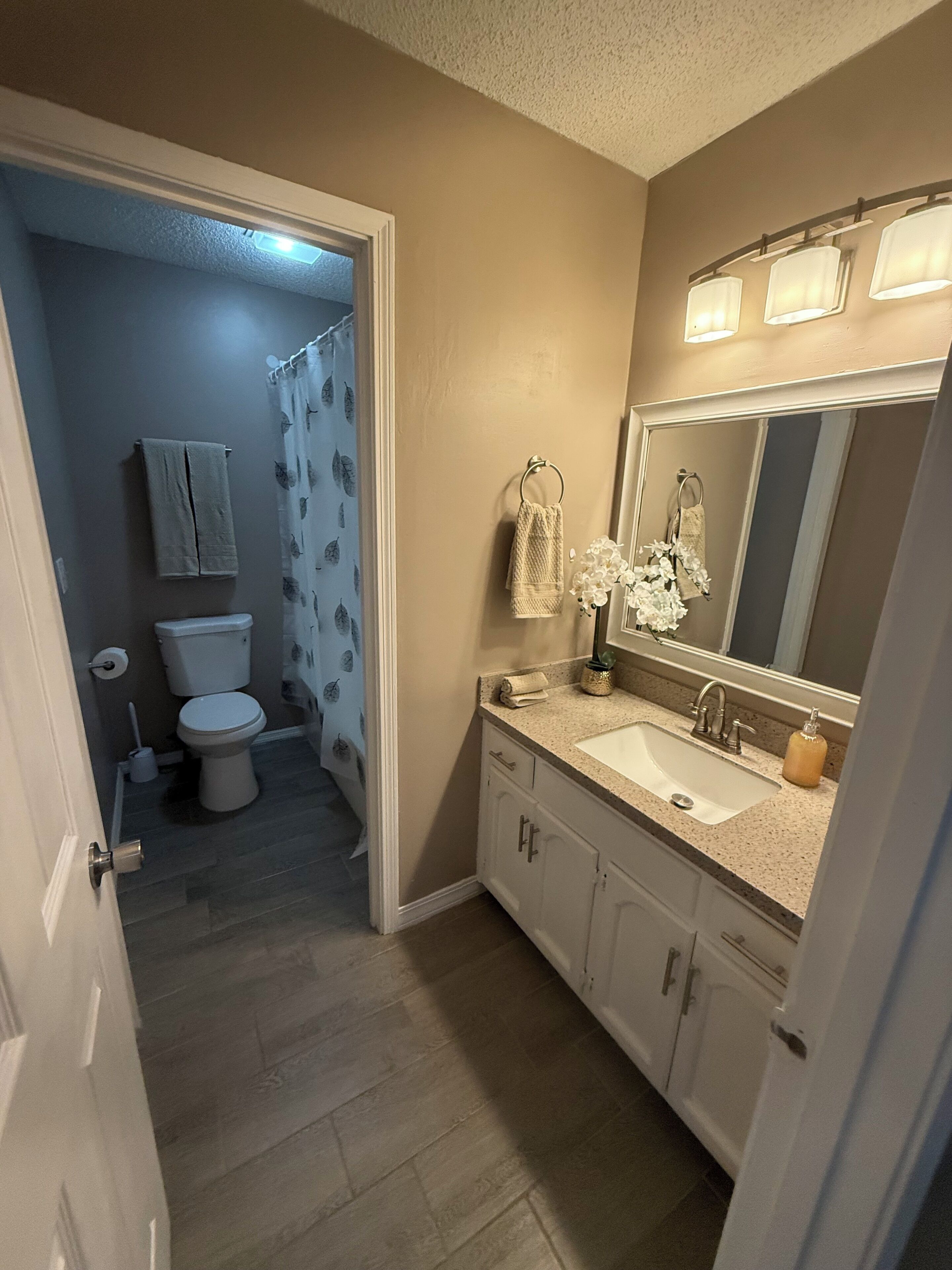 Un baño con inodoro, lavabo, espejo y cortina de ducha.