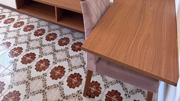 A room with a television mounted on the wall, a wooden table, and patterned floor tiles. - Vacation Apartment 400 meters from Castanheiras Beach/Guarapari City Center (Guarapari)
