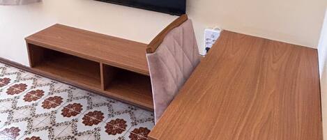Una habitación con televisión montada en la pared, una mesa de madera y baldosas de suelo con diseño.