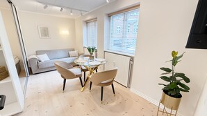 A modern living room with a glass dining table, two chairs, a sofa, and a potted plant. - Det Gamle Vaskeri - Historical Apartment in Horsens (Horsens)
