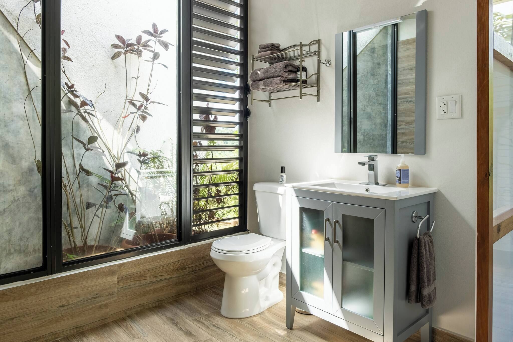 A modern bathroom with a toilet, sink, and mirror.