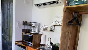 Una cuina compacta amb nevera, microones, cafetera i un taulell de fusta.