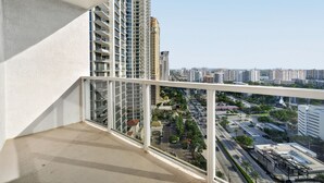Ein Balkon mit Blick auf eine Stadtlandschaft, darunter Wolkenkratzer und eine Straße mit Fahrzeugen.
