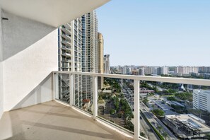 Ein Balkon mit Blick auf eine Stadtlandschaft, darunter Wolkenkratzer und eine Straße mit Fahrzeugen.