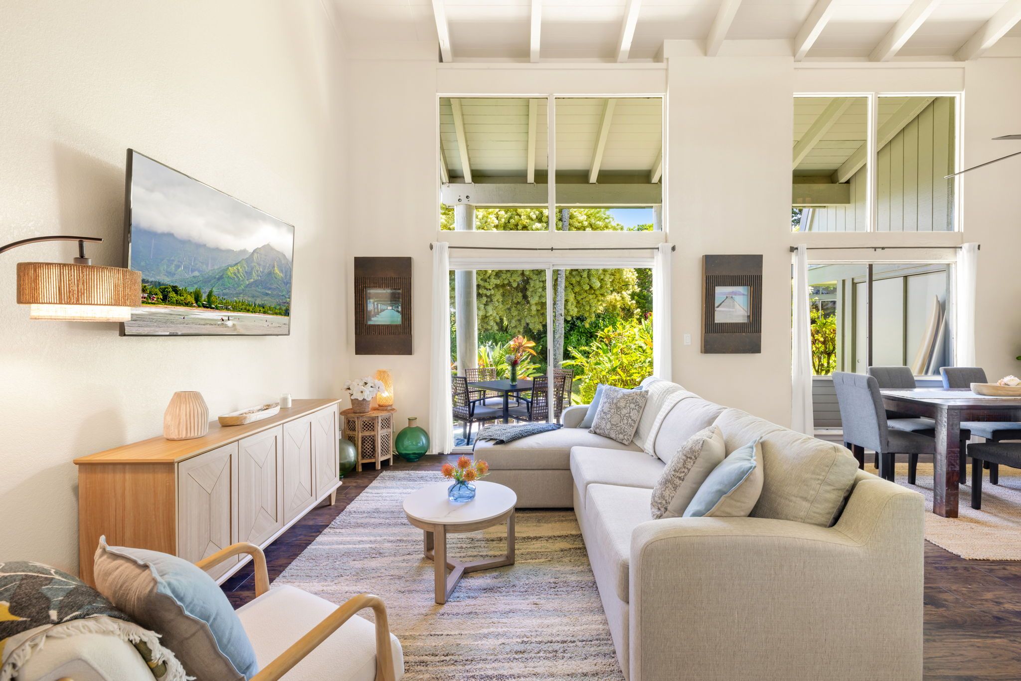 A spacious living area with a large sofa, a coffee table, and a television mounted on the wall.