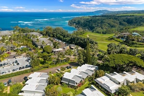 Um resort costeiro com vários edifícios no estilo de bangalôs, um estacionamento e um campo de golfe.