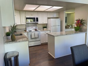 Une cuisine moderne avec des meubles blancs, une cuisinière en acier inoxydable et un four à micro-ondes encastré.