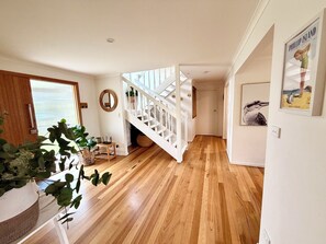 Eine Treppe führt zu einer zweiten Etage, ein Holzboden, ein Spiegel an der Wand und ein gerahmtes Bild.