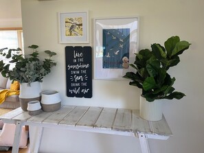 Un mur orné de tableaux encadrés, une citation inspirante et des plantes en pot.
