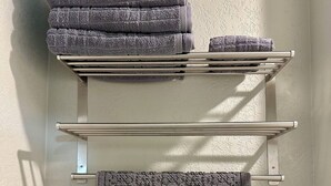 A bathroom with a towel rack holding folded towels and a decorative towel. - ROOM 23. Angry Salmon Inn (Anchor Point)