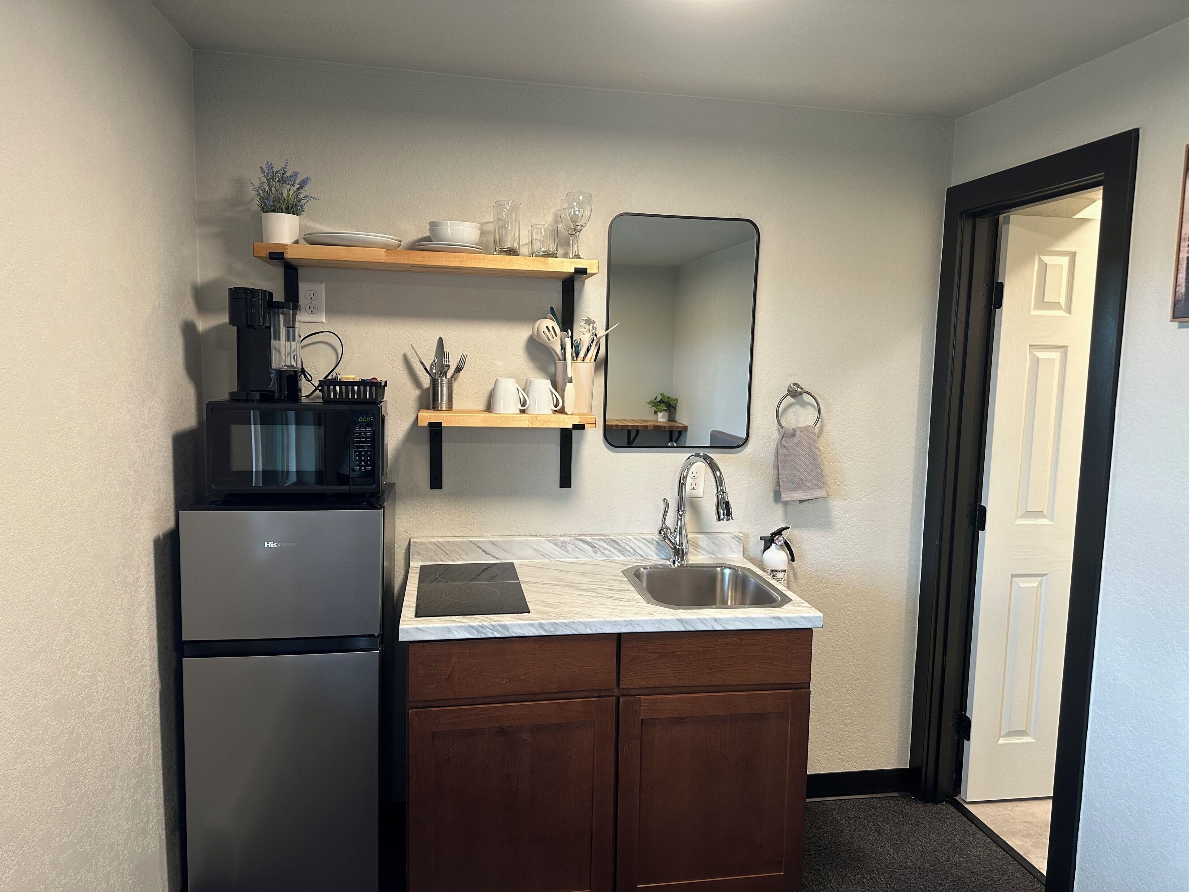 A compact kitchen with a refrigerator, microwave, sink, and wooden cabinets.