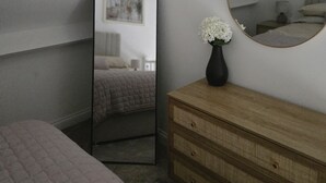 A bedroom with a bed, dresser, mirror, and a ceiling light fixture.