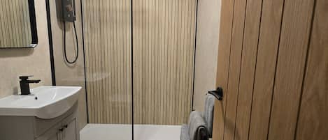 A bathroom with a shower, sink, and mirror.