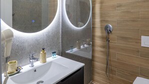 A modern bathroom with a large mirror, a sink, and a shower.