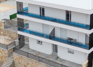 Un immeuble à plusieurs étages doté de balcons, d’une piscine et d’un escalier en pierre.