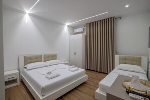 A modern hotel room with a large bed, bedside tables, a wardrobe, and a bathroom. - SulMare Rooms (Sarandë)