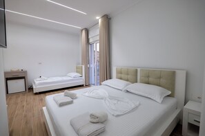 A hotel room with a large bed, a smaller bed, a desk, and a bathroom. - SulMare Rooms (Sarandë)