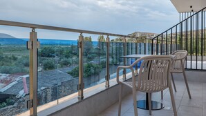 A balcony with a glass railing, a table, and two chairs.