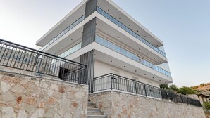 A multi-story building with a stone facade and a metal railing.