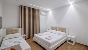 A modern hotel room with a bed, bedside tables, a TV, and a window with curtains.