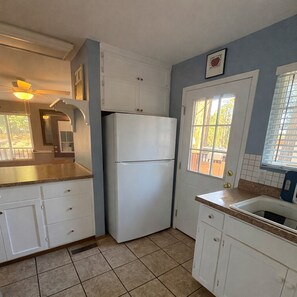 A kitchen with a refrigerator, cabinets, a window, and a ceiling fan. - Cozy Home in Pioneer (Pioneer)
