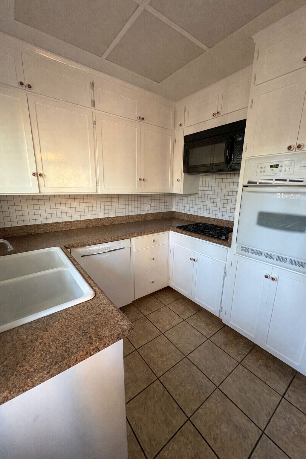 Una cocina con armarios blancos, un microondas, una estufa y un refrigerador.