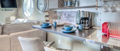 Um espaço compacto com cozinha compacta, sofá e área de bar com café.
