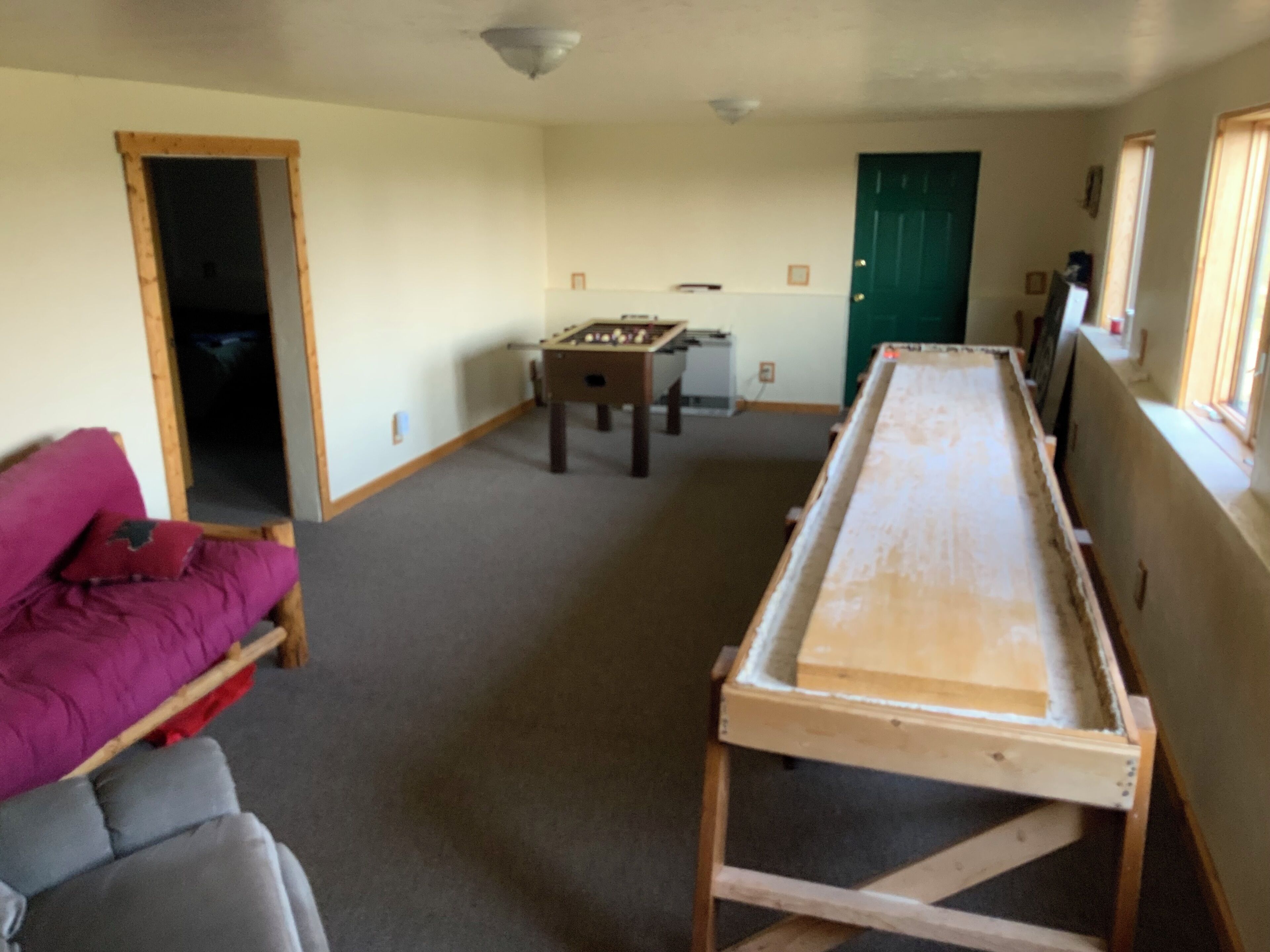 A room with a foosball table, a sofa, and a long table.