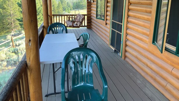 Une cabane en bois avec une véranda, une table et deux chaises.