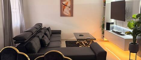 Una sala de estar moderna con un sofá, una mesa de centro, un televisor y un ventilador de techo.